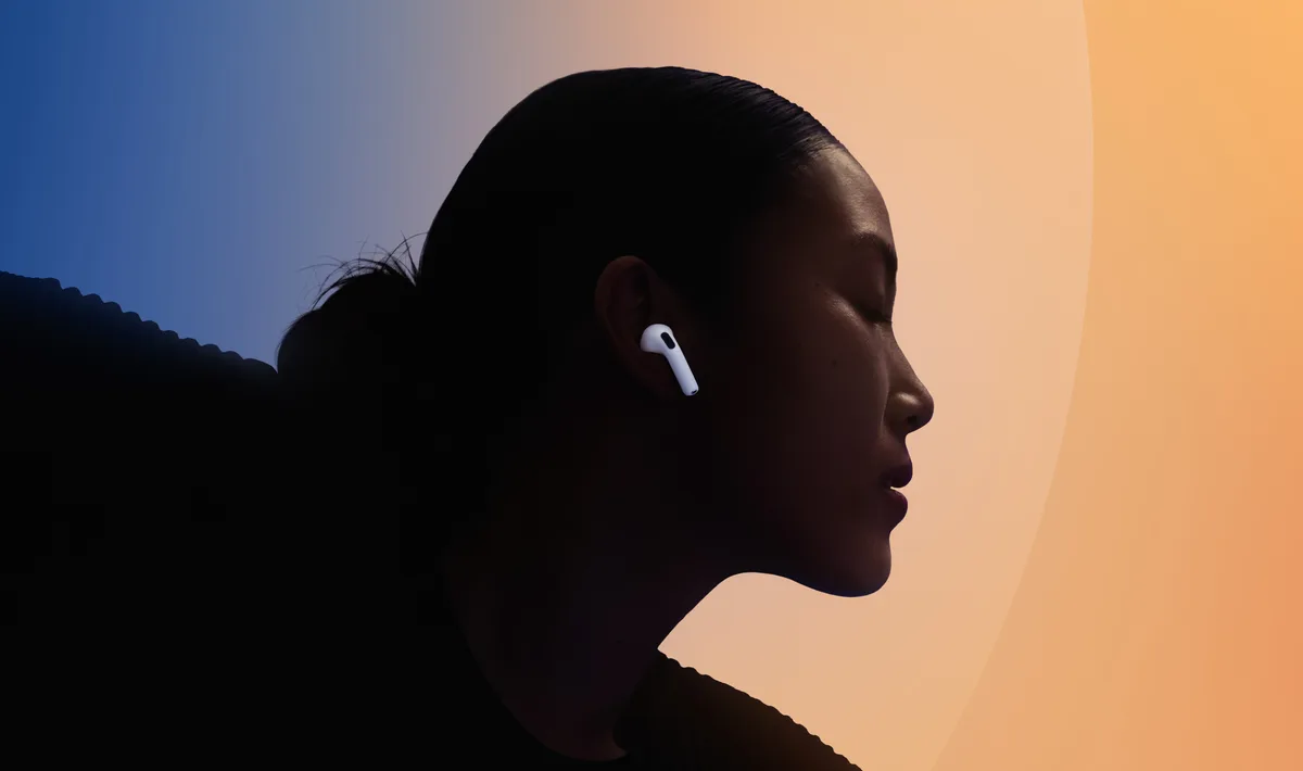 Silhouette wearing AirPods 4 with active noise cancellation against blue and orange gradient