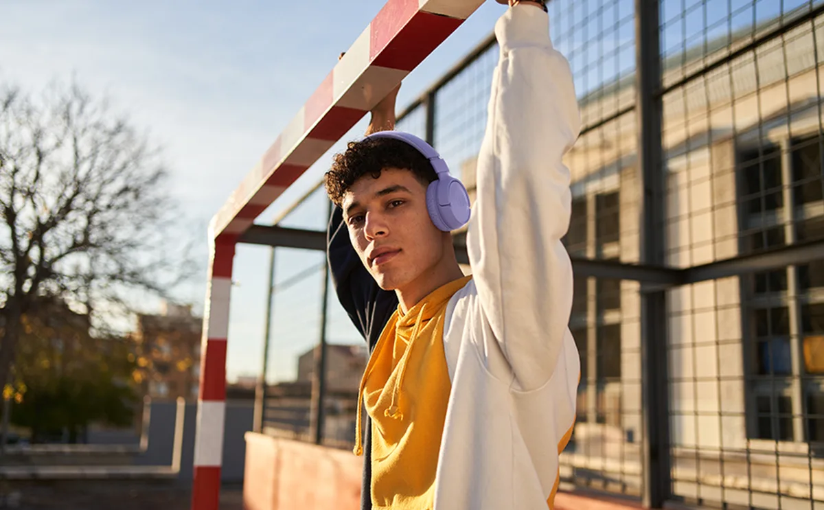 Young man wearing JBL Tune 520BT headphones outdoors in urban setting