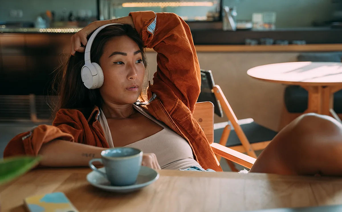 Young woman wearing JBL Tune 520BT headphones in white, outdoor lifestyle