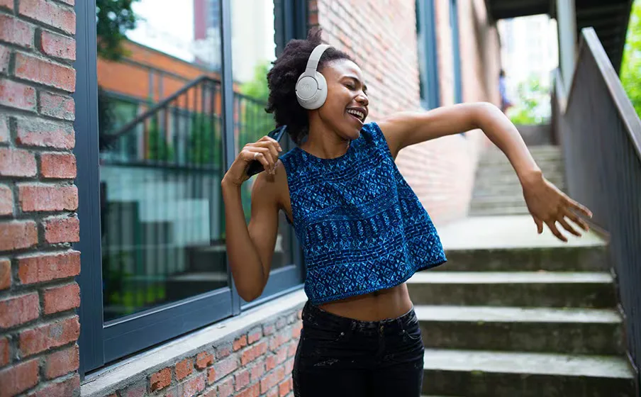 Woman dancing outdoors wearing JBL Tune 770NC headphones