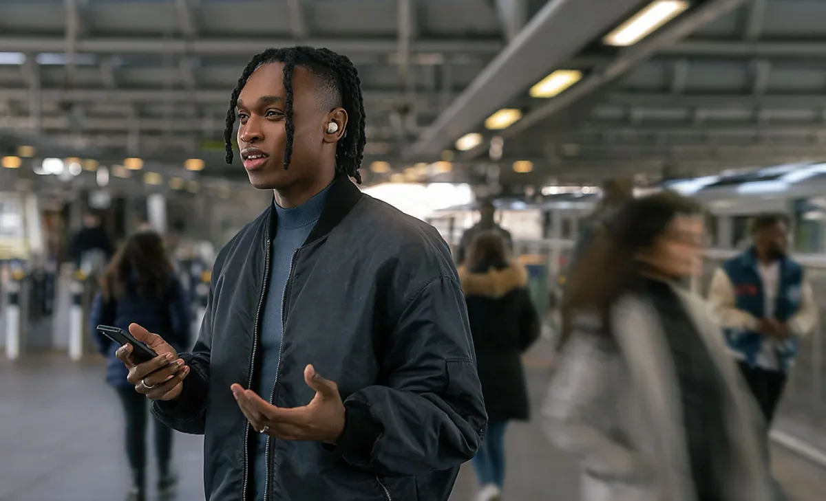 Man wearing Sony WF-1000XM5 earbuds in urban transit station