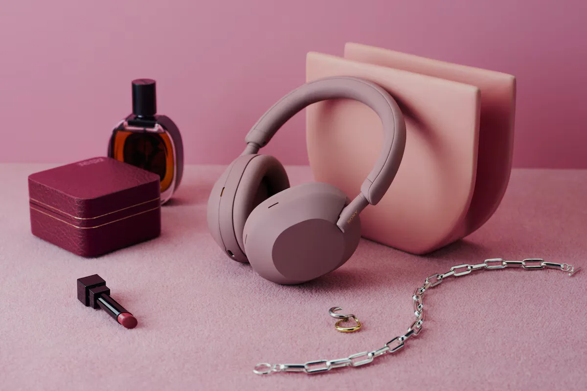 Sony WH-1000XM5 headphones styled with fashion accessories on pink surface