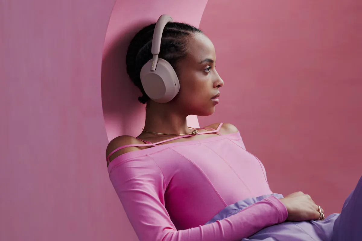Woman wearing Sony WH-1000XM5 relaxing against wall