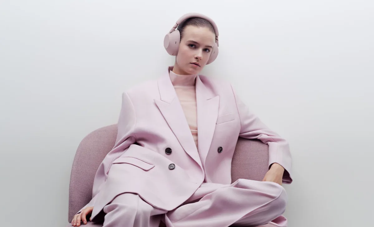 Woman wearing Sony WH-1000XM6 seated in pink outfit, fashion lifestyle