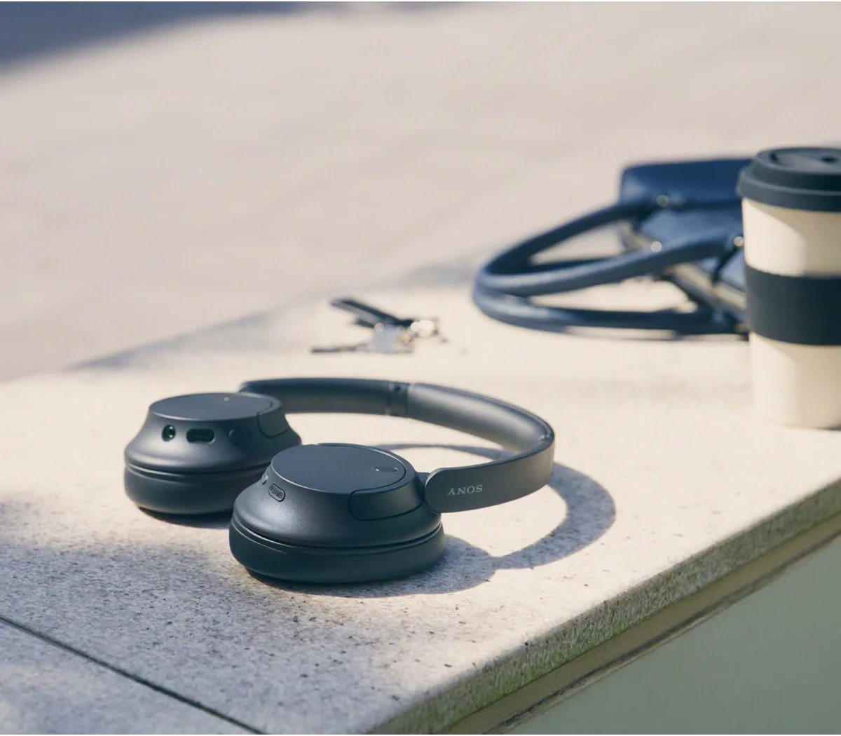 Sony WH-CH720N folded beside coffee outdoors